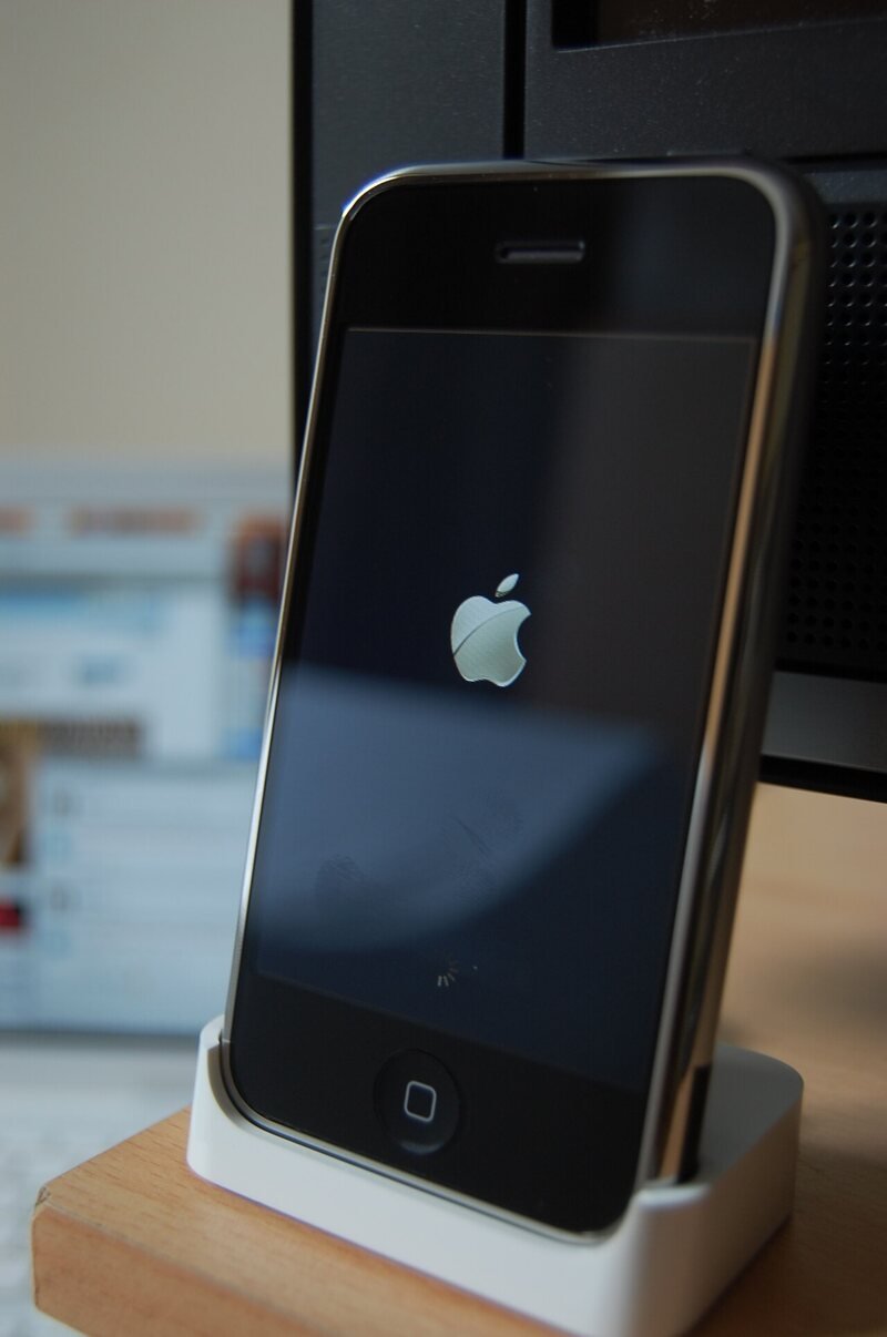An original 2007 iPhone standing in its white dock